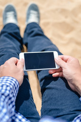 Top view closeup on man holding phone on the beach outside background
