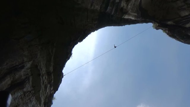 Tightrope walker 230 feet high in blue sky
