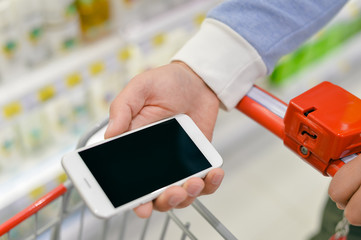 Man holding smart phone and reading text message during shopping