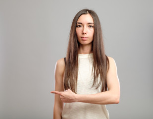 Girl pointing isolated on gray