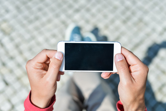 Top view of person sitting on bench hands holding smartphone 