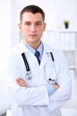 Friendly male doctor in the hospital office. Ready to examine and help patients. High level and quality medical service concept. Best treatment and patient care concept