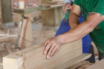 A pair of powerful arms, the craftsman is planing wood,