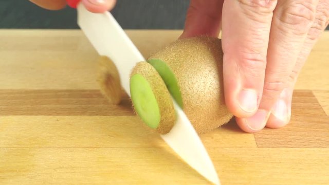 Slicing kiwi with white ceramic knife