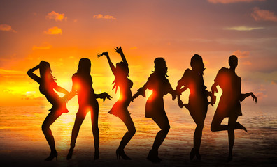 Dancing girls silhouettes against of sunset at the beach