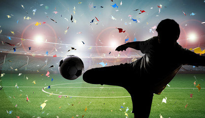 silhouette football player kicking the ball with stadium background