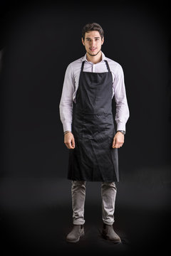 Young chef or waiter wearing black apron 