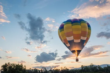 Rolgordijnen heteluchtballon vliegt bij zonsopgang © pongpinun