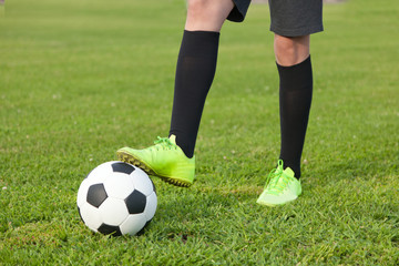 Soccer ball and a football player  legs on a green lawn, close-u