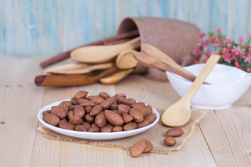Almonds in brown bowl on textured wooden background