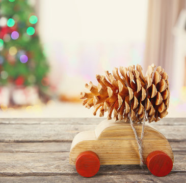 Wooden toy car carrying Christmas pine on shiny lights background