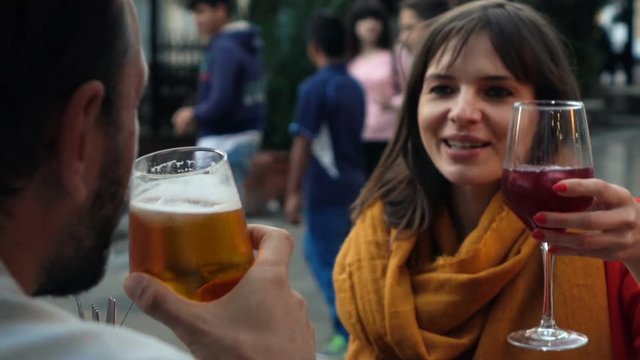 Young couple drinking wine and beer in outdoor cafe in the city, super slow motion
