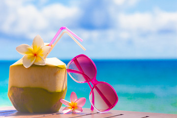 picture of fresh coconut cocktail and pink sunglasses on tropical beach