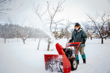Man using snow blower in snowy field