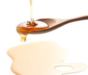 syrup pouring on spoon on white background
