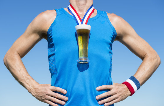 American athlete standing with first place gold medal in the shape of a glass of beer standing in front of blue sky