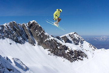 Naklejka na ściany i meble Ski rider jumping on mountains. Extreme ski freeride sport.
