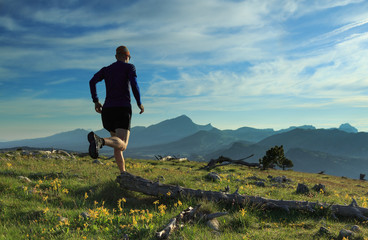 Athlete trailrunning in the mountains during a nice sunrise.