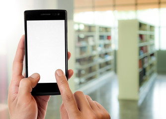 Hand holding smart phone on blur library room background