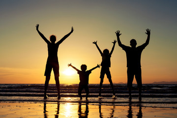 Silhouette of happy family who standing on the beach at the suns