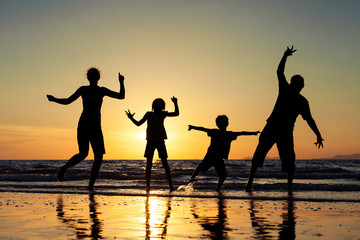 Fototapeta na wymiar Silhouette of happy family who standing on the beach at the suns