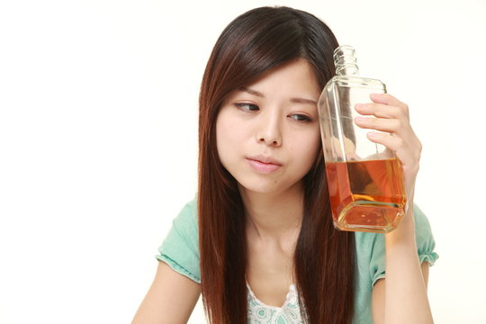 young Japanese woman wearing a green summer dress drinking straight from a bottle