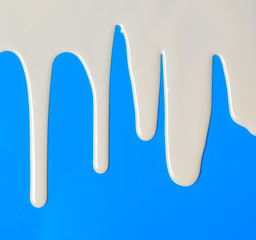Dripping white milk, cream, paint yogurt on blue background
