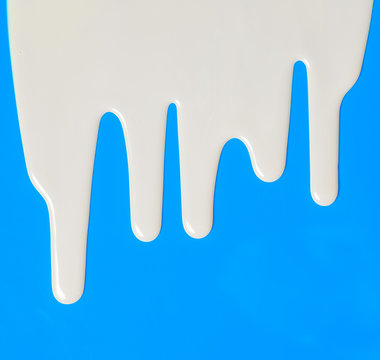 Dripping white milk, cream, paint yogurt on blue background