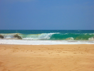 Empty ocean beach with yellow clear sand and blue waves