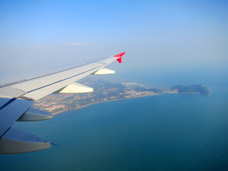 Fototapeta premium Plane wing in a blue sky above Kuala-Lumpur