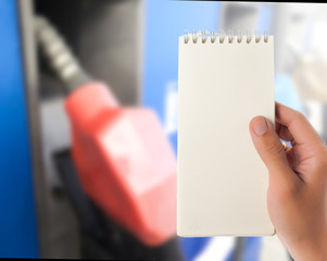 Hand hold blank notepad with space for text,Blur fuel dispenser