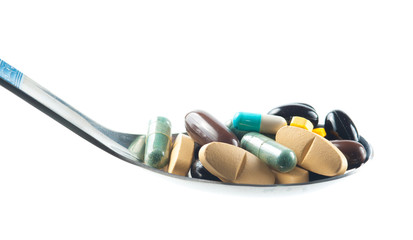 Various drugs vitamins and nutrition supplements on spoon.