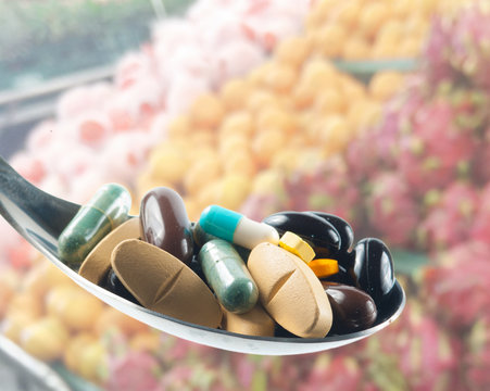 Various drugs vitamins and on spoon,Blur fruits background