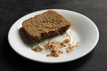 brown bread in a plate on a black background.The concept of poverty