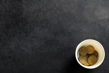 a penny in Cup on black background.The concept of poverty