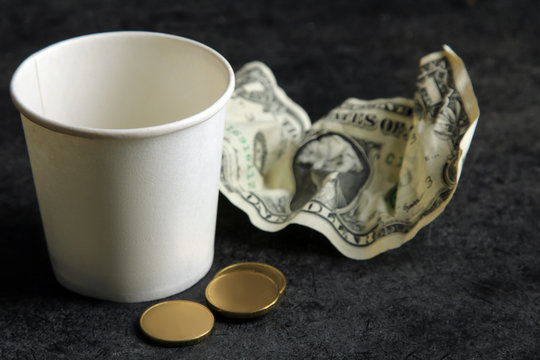 a penny and a dollar and a Cup on black background.The concept of poverty