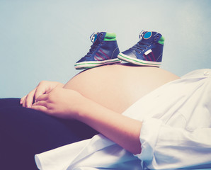 Pregnant woman with baby shoe on the stomach,vintage color toned