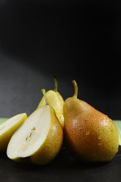 Fresh ripe organic pears on green and black background