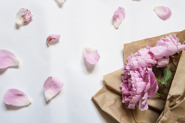 Floral frame with pink peonies bouquet and petals on white background
