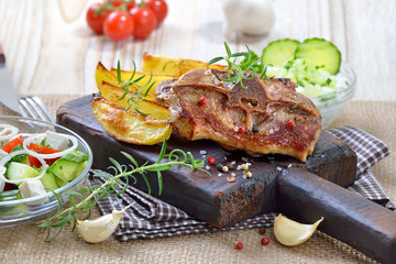 Gebratene Lammkoteletts mit Potato wedges, griechischem Bauernsalat und Tzatziki rustikal serviert...