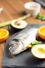 two raw dorado fish with lemon, spices and spoon on paper, composing on white wooden background, top view