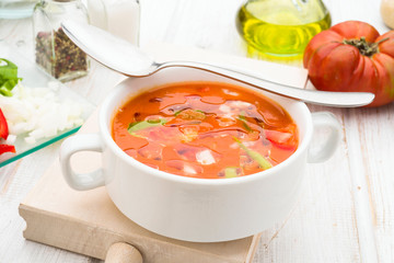 gazpacho soup with oil and spoon in white bowl