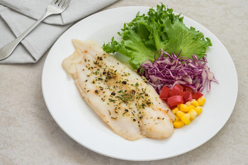 Grilled fish fillet steak with herb and vegetables on plate