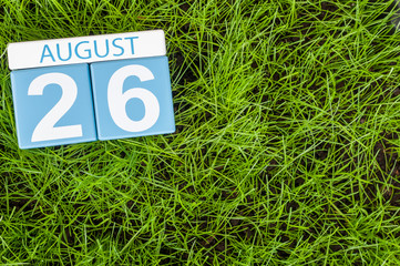 August 26th. Image of august 26 wooden color calendar on green grass lawn background with soccer ball. Summer day. Empty space for text