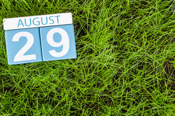 August 29th. Image of august 29 wooden color calendar on green grass lawn background with soccer ball. Summer day. Empty space for text