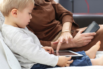 son learning and using tablet with his mother