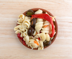 Small bowl of rotini pasta salad on wood table top view.