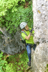Junge klettert eine senkrechte Felswand im Klettersteig hoch