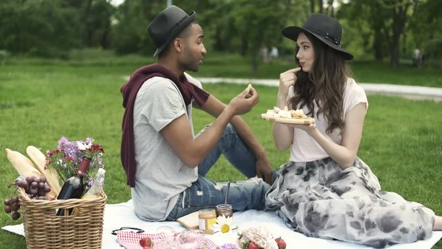 Smiling young couple having picnic on grass in park