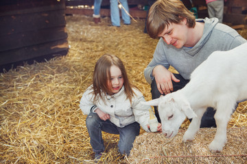 Child and father taming a goat kid